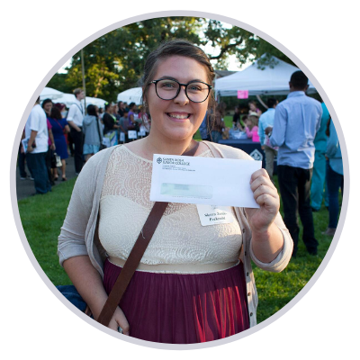 smiling student holding up her scholarship check