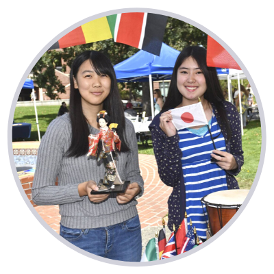 Two international students holding a flag and asian doll
